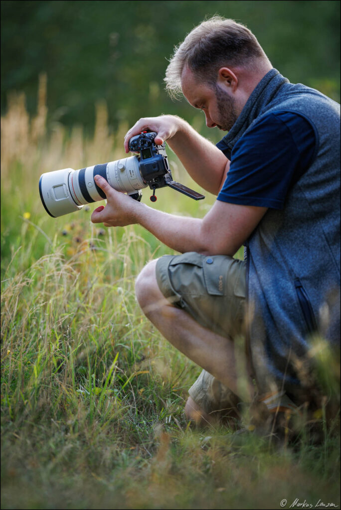 Naturfotograf Markus Lenzen mit Kamera in einer Wiese